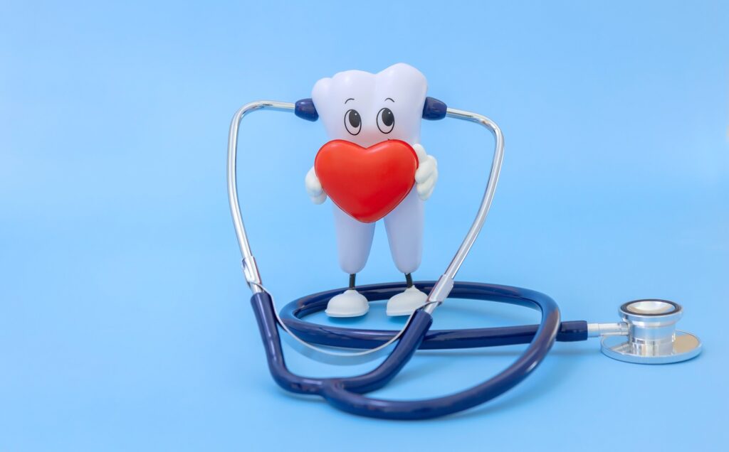 Cartoon tooth holding a heart with a stethoscope symbolizing the connection between oral health and heart health