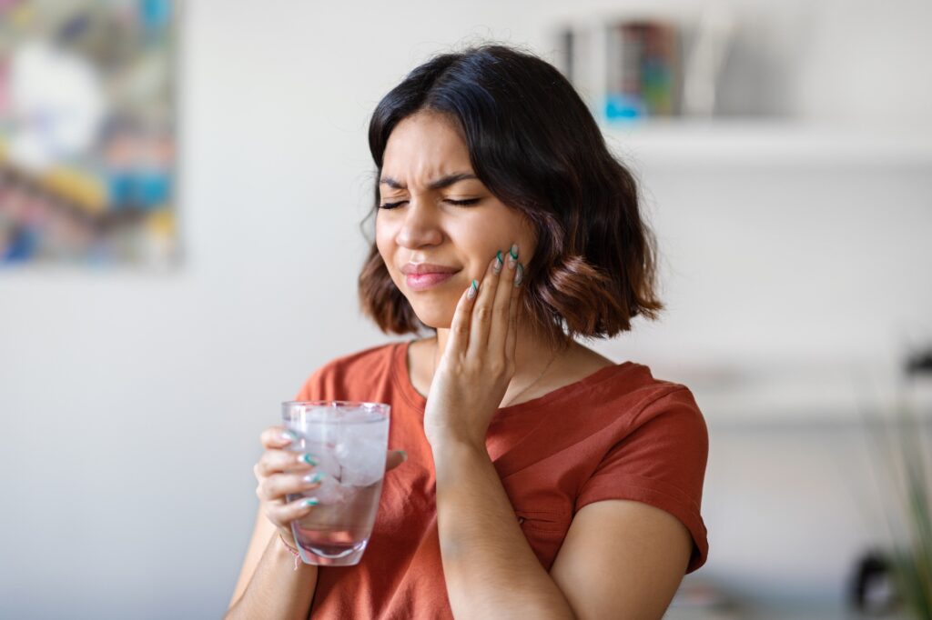 Person reacting to tooth sensitivity from cold drink